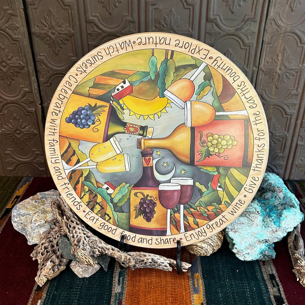 Wooden lazy susan with decorative designs such as grape vines, painted wine, and the sky in vibrant colors.