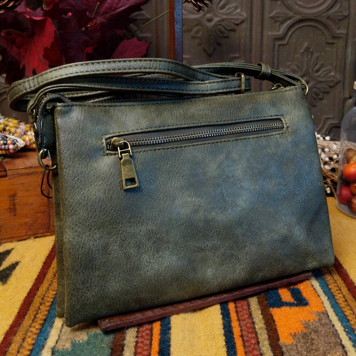 Lexi Crossbody Bag by Liz Soto featuring a streamlined silhouette, textured exterior, envelope-style front pocket, adjustable shoulder strap, metal hardware, and Liz Soto logo; back view.
