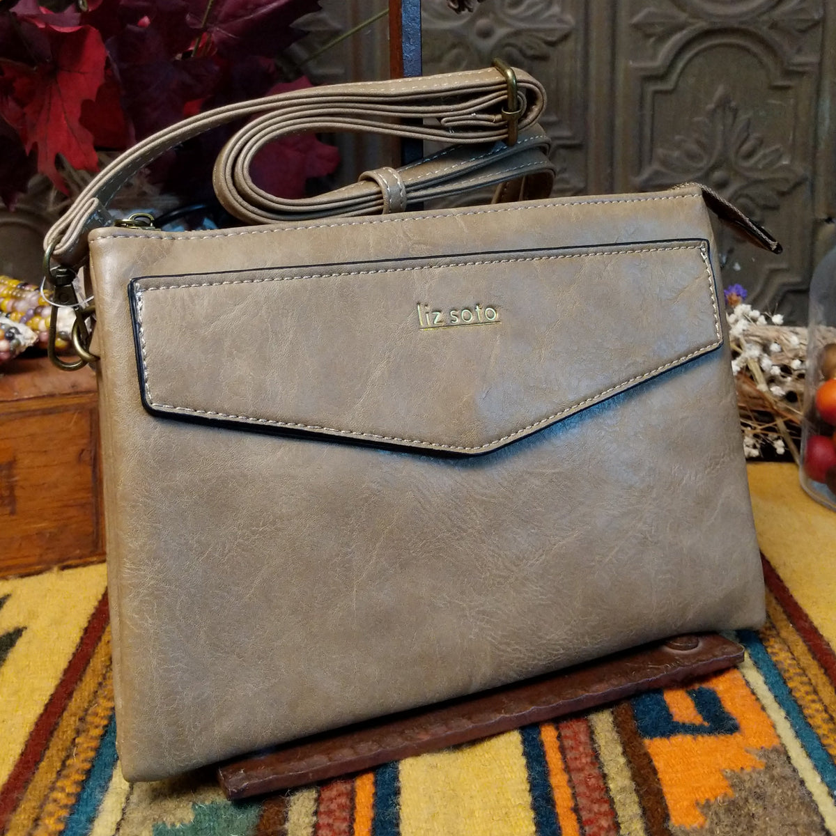 Lexi Crossbody Bag by Liz Soto featuring a streamlined silhouette, textured exterior, envelope-style front pocket, adjustable shoulder strap, metal hardware, and Liz Soto logo.