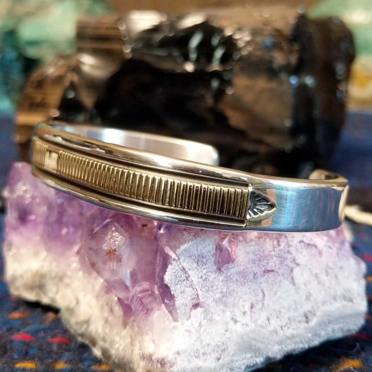 Polished sterling silver and gold cuff featuring intricate line-work.