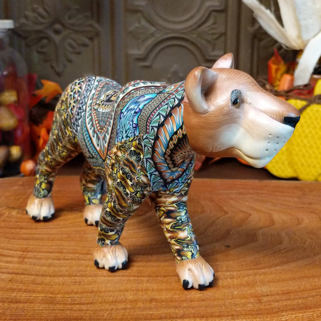 Polymer clay lioness with detailed face and vibrant designs all along the body.