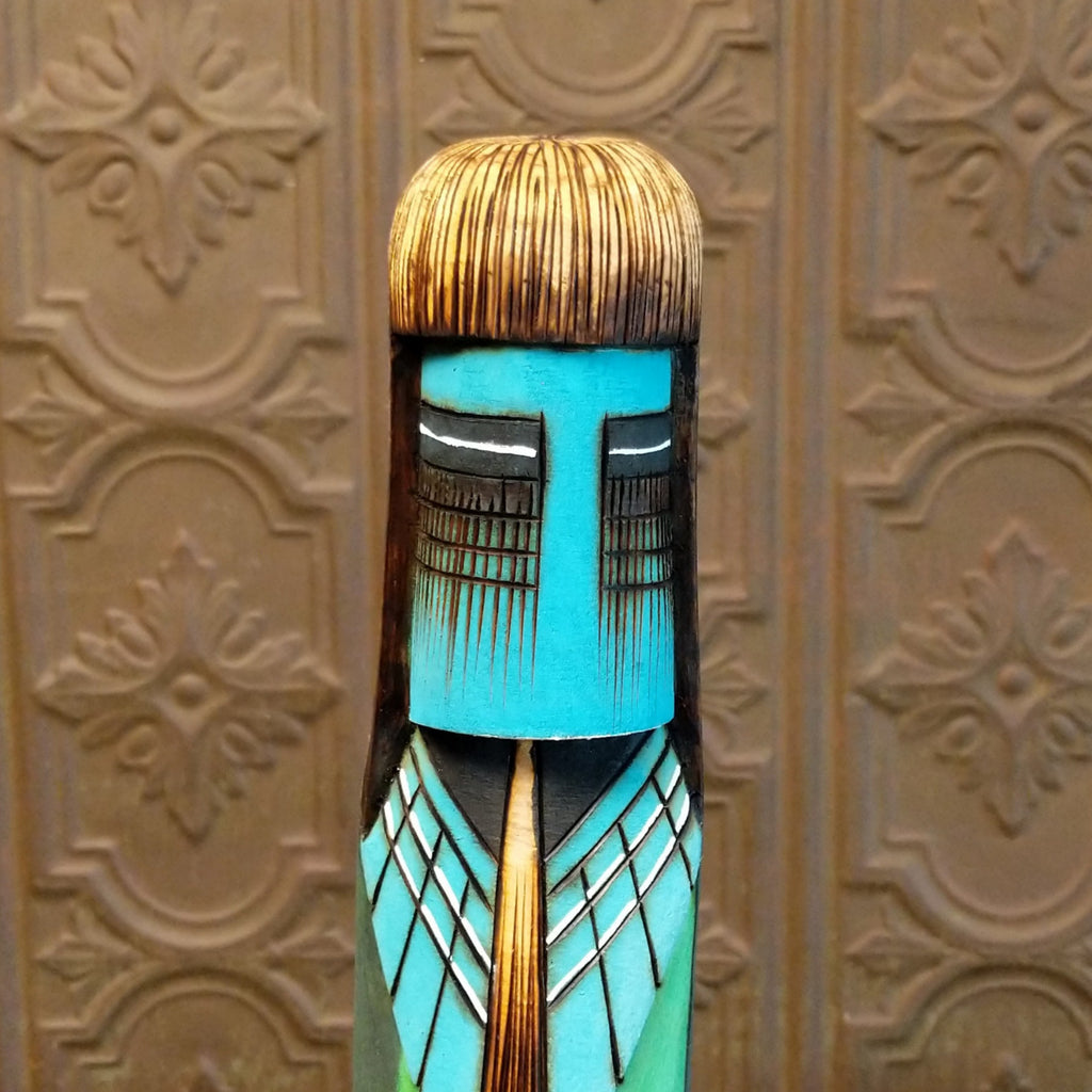 A close-up of the blue face and long hair of the totem.