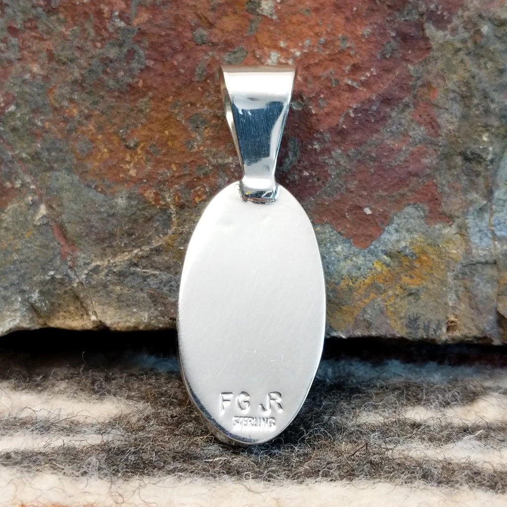 The back of the pendant features the artisan's initials.