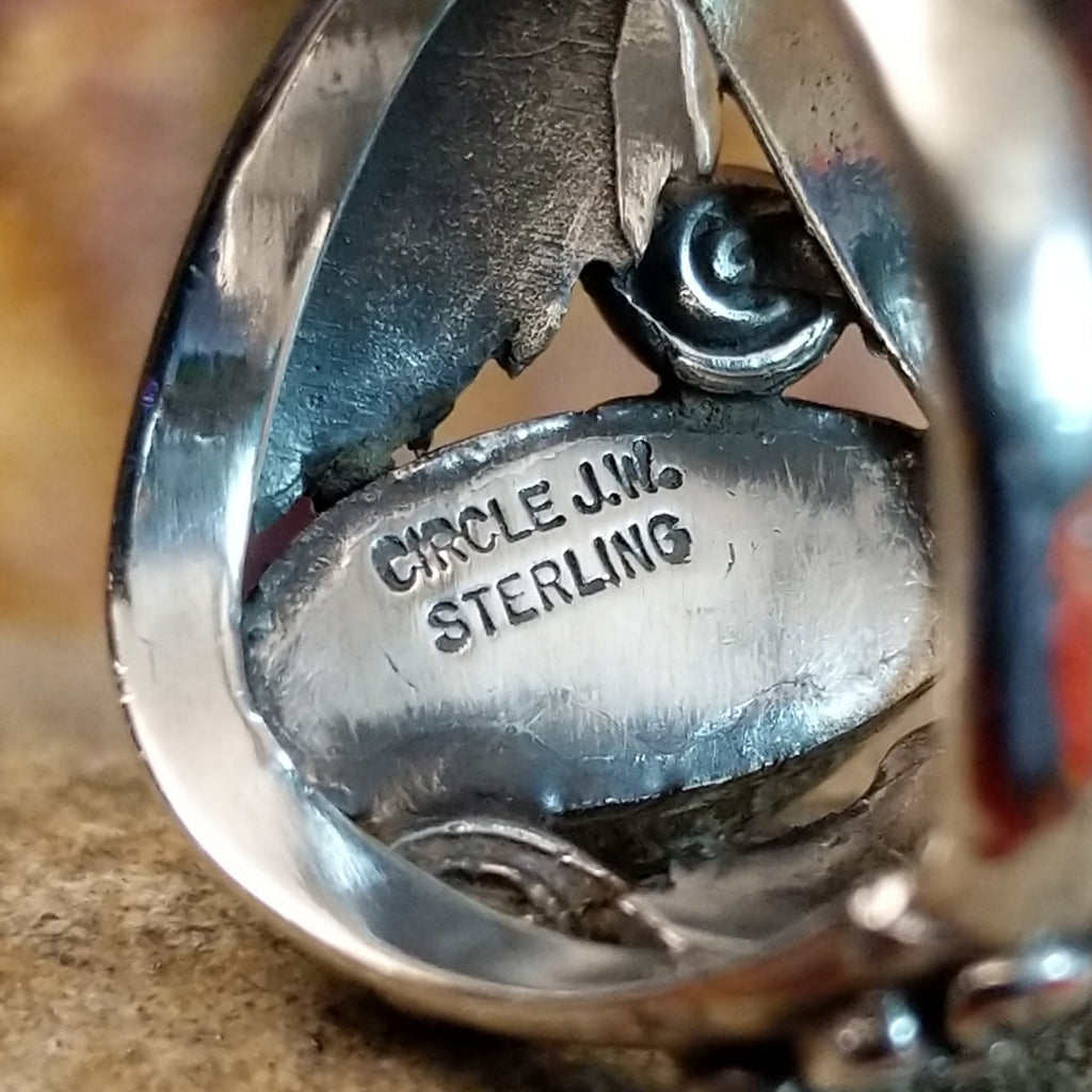 The artist's signature is stamped on the inside of the setting.