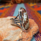 Long Oval Wild Horse Ring by John King featuring a large Wild Horse stone with brown, rust, cream, and white matrix set in Sterling Silver with detailed silverwork and a split-shank band; side view.