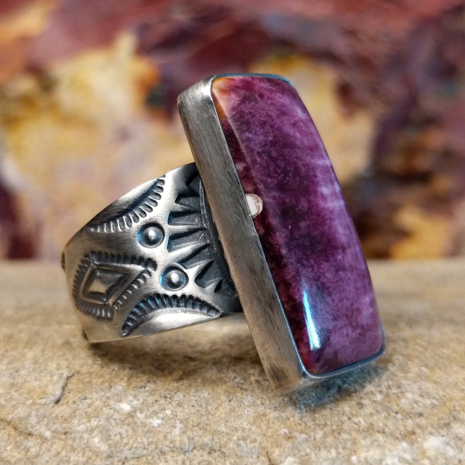 Long rectangular purple spiny oyster shell set in a smooth bezel with an intricately stamped band.