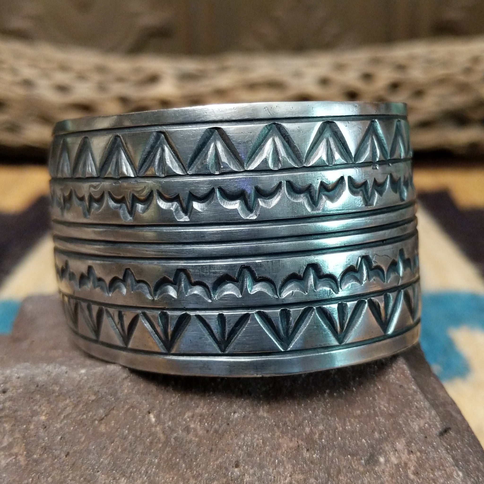 Longhorn stamped sterling silver cuff by E. Piaso, featuring bold geometric hand-stamped longhorn-inspired patterns on a handcrafted wide sterling silver open cuff.