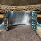 Longhorn stamped sterling silver cuff by E. Piaso, featuring bold geometric hand-stamped longhorn-inspired patterns on a handcrafted wide sterling silver open cuff.  Underside view.
