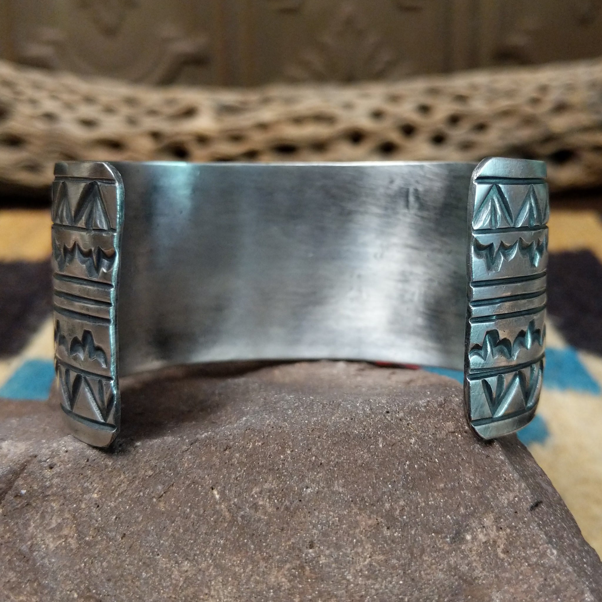Longhorn stamped sterling silver cuff by E. Piaso, featuring bold geometric hand-stamped longhorn-inspired patterns on a handcrafted wide sterling silver open cuff.  Underside view.