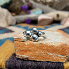 Handcrafted Navajo sterling silver ring by Leon Martinez featuring four graduated polished silver domes in a modern open-loop design with a high-polish finish.