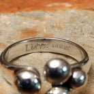 Handcrafted Navajo sterling silver ring by Leon Martinez featuring four graduated polished silver domes in a modern open-loop design with a high-polish finish; artisan and Sterling Silver stamp.