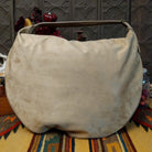 Lulu Handbag by Liz Soto featuring a spacious hobo silhouette, soft suede-like exterior, long shoulder strap, side buckle detailing, top zip closure, and logo plaque; back.