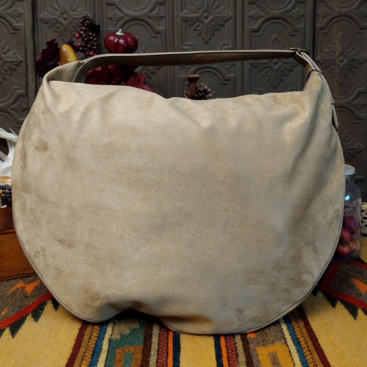 Lulu Handbag by Liz Soto featuring a spacious hobo silhouette, soft suede-like exterior, long shoulder strap, side buckle detailing, top zip closure, and logo plaque; back.
