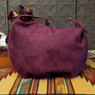 Lulu Handbag by Liz Soto featuring a spacious hobo silhouette, soft suede-like exterior, long shoulder strap, side buckle detailing, top zip closure, and logo plaque; back.