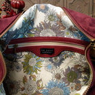 Lulu Handbag by Liz Soto featuring a spacious hobo silhouette, soft suede-like exterior, long shoulder strap, side buckle detailing, top zip closure, and logo plaque; interior zipper.