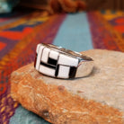 Magnesite & Black Onyx Ring by Karen Skeet featuring geometric white magnesite and black onyx inlay separated by fine silver channels across a wide polished silver band; side view.