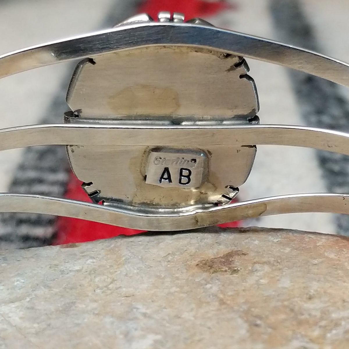 Silver cuff by Amory Begay featuring a large oval malachite stone with sweeping bands of dark and vivid green, surrounded by geometric silver accents and split silver bands; artisan and Sterling Silver stamp.