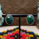Malachite Oval Earrings by Priscilla Smith featuring polished deep-green malachite cabochons with natural banding, set in silver with twisted rope-style borders.