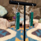 Handcrafted sterling silver pillar earrings by Juan Willie featuring rectangular natural malachite with vibrant green banding and French hook ear wires; side view.