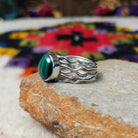 Graceful Malachite Ring by Angela Martin featuring an oval green banded malachite stone set in sterling silver with flowing wave-like silver strands; side view.