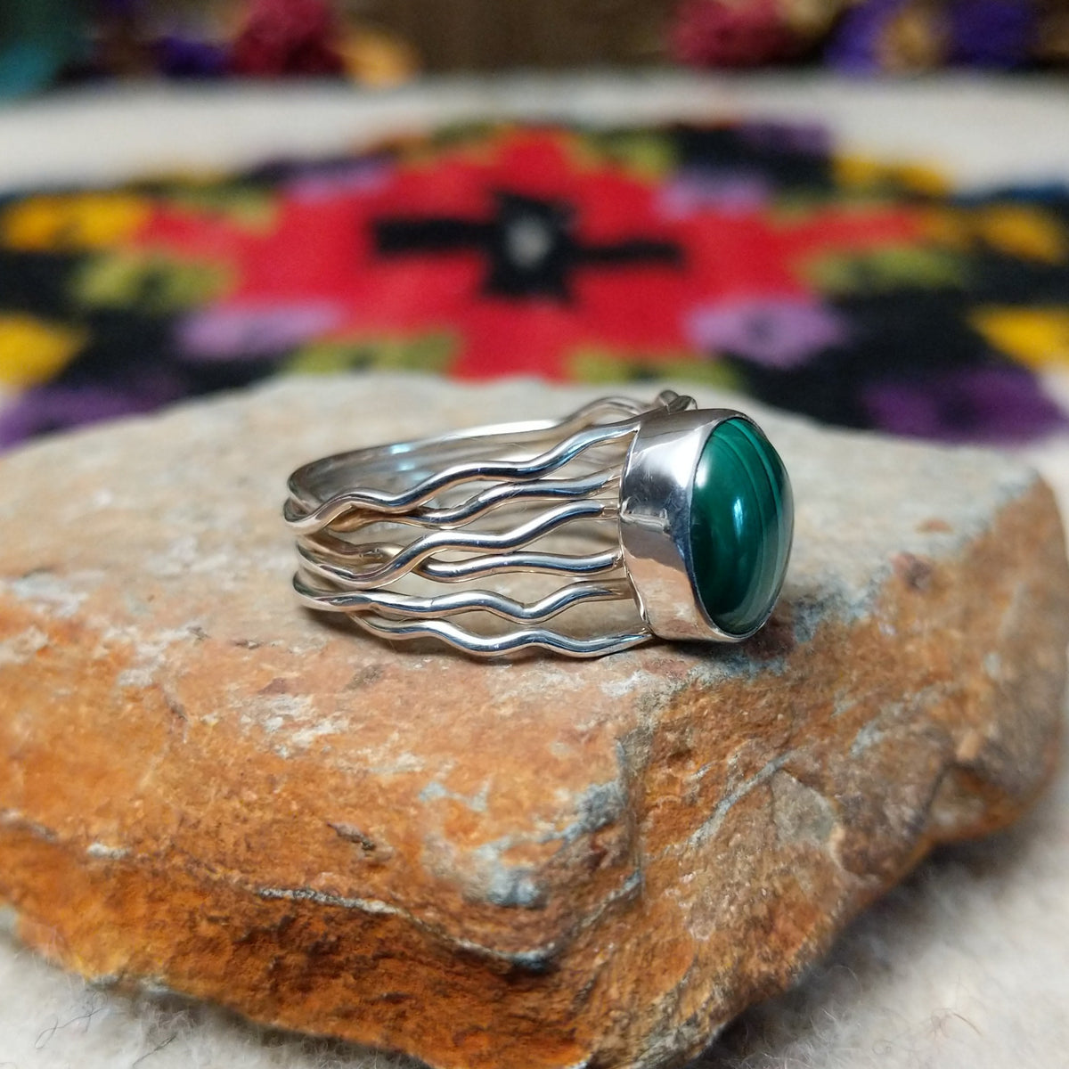 Graceful Malachite Ring by Angela Martin featuring an oval green banded malachite stone set in sterling silver with flowing wave-like silver strands; side view.