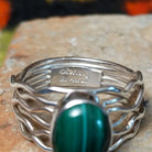 Graceful Malachite Ring by Angela Martin featuring an oval green banded malachite stone set in sterling silver with flowing wave-like silver strands; artisan and Sterling Silver stamp.