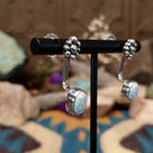Handcrafted sterling silver adjustable earrings by Terry Wood featuring oval manmade opal cabochons with colorful iridescence and traditional Navajo silver bead cluster accents; side view.