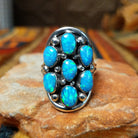 This dazzling Manmade Blue Opal Cluster Ring by D.D. features seven oval blue opal stones with vibrant blue and green flashes, accented by silver beads and oxidized detailing.