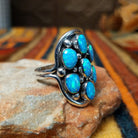 This dazzling Manmade Blue Opal Cluster Ring by D.D. features seven oval blue opal stones with vibrant blue and green flashes, accented by silver beads and oxidized detailing; side view.
