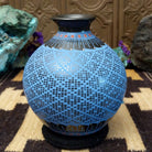 Blue Mata Ortiz pottery vase with a flared black neck, featuring intricate geometric patterns of small black squares and red accent details near the rim.