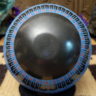Blue Mata Ortiz pottery vase with a flared black neck, featuring intricate geometric patterns of small black squares and red accent details near the rim.
