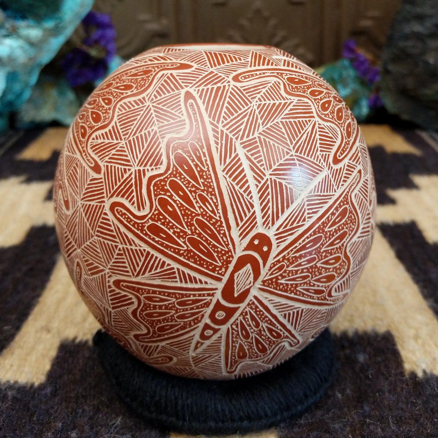 Round Mata Ortiz pottery vessel featuring an etched butterfly design in warm clay tones with intricate geometric linework across the surface.