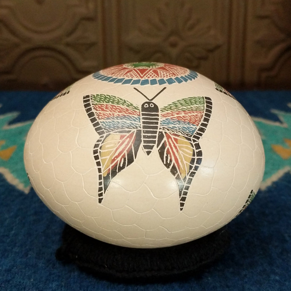 White clay seed pot with three colorful butterflies and geometric designs.