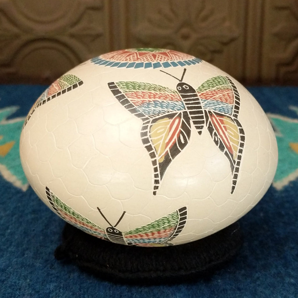 White clay seed pot with three colorful butterflies and geometric designs.