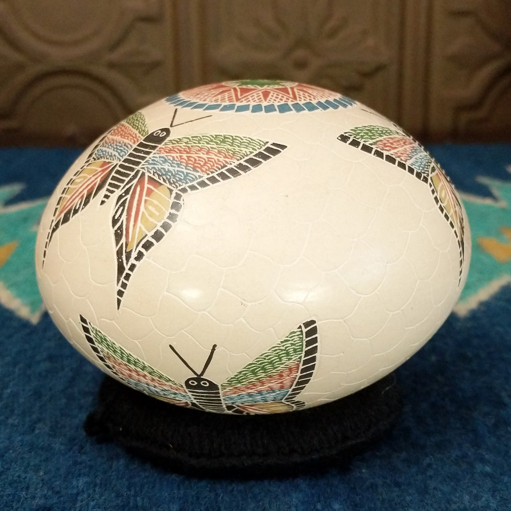 White clay seed pot with three colorful butterflies and geometric designs.