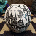 Round Mata Ortiz pottery vessel featuring an etched black and white Day of the Dead scene. 