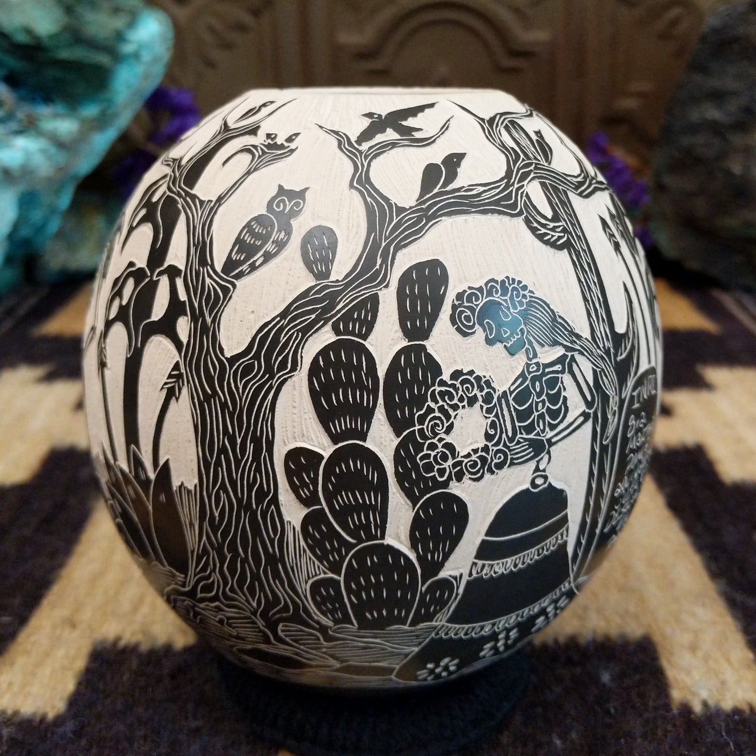 Round Mata Ortiz pottery vessel featuring an etched black and white Day of the Dead scene. 