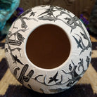 Round Mata Ortiz pottery vessel featuring an etched black and white Day of the Dead scene. 