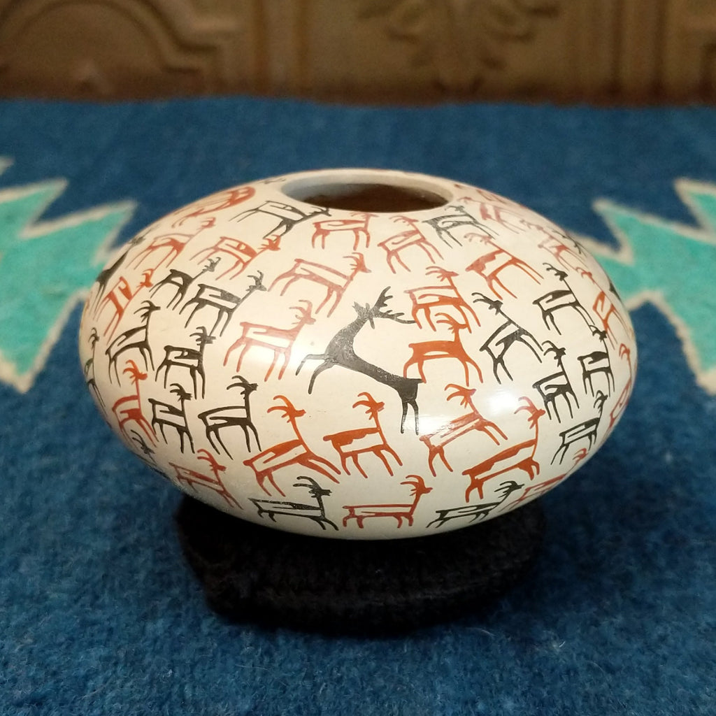 White clay seed pot with deer pictograph patterns on the surface.