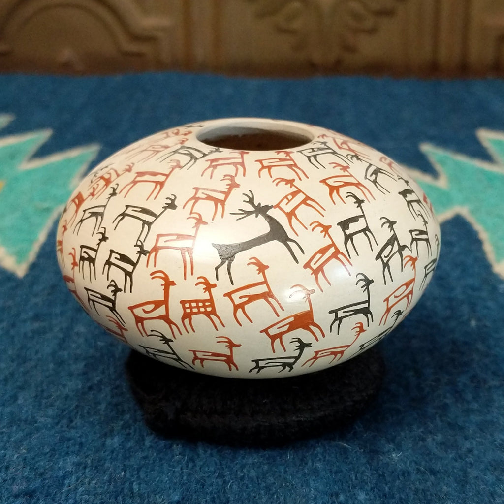 White clay seed pot with deer pictograph patterns on the surface.