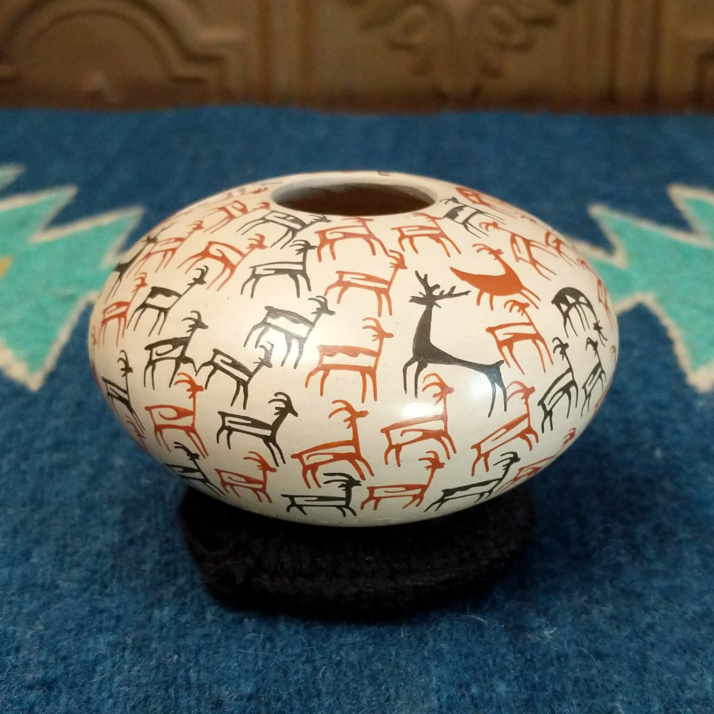 White clay seed pot with deer pictograph patterns on the surface.