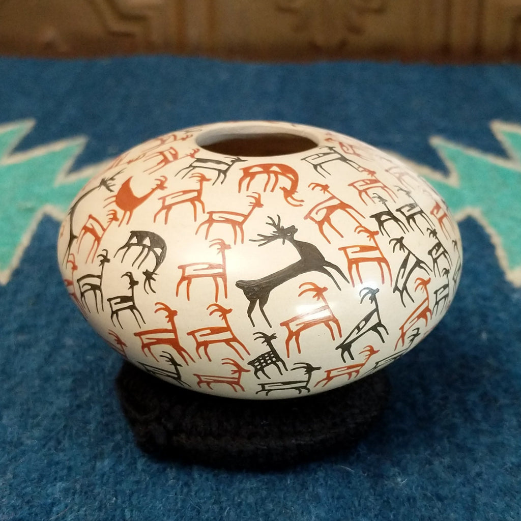 White clay seed pot with deer pictograph patterns on the surface.