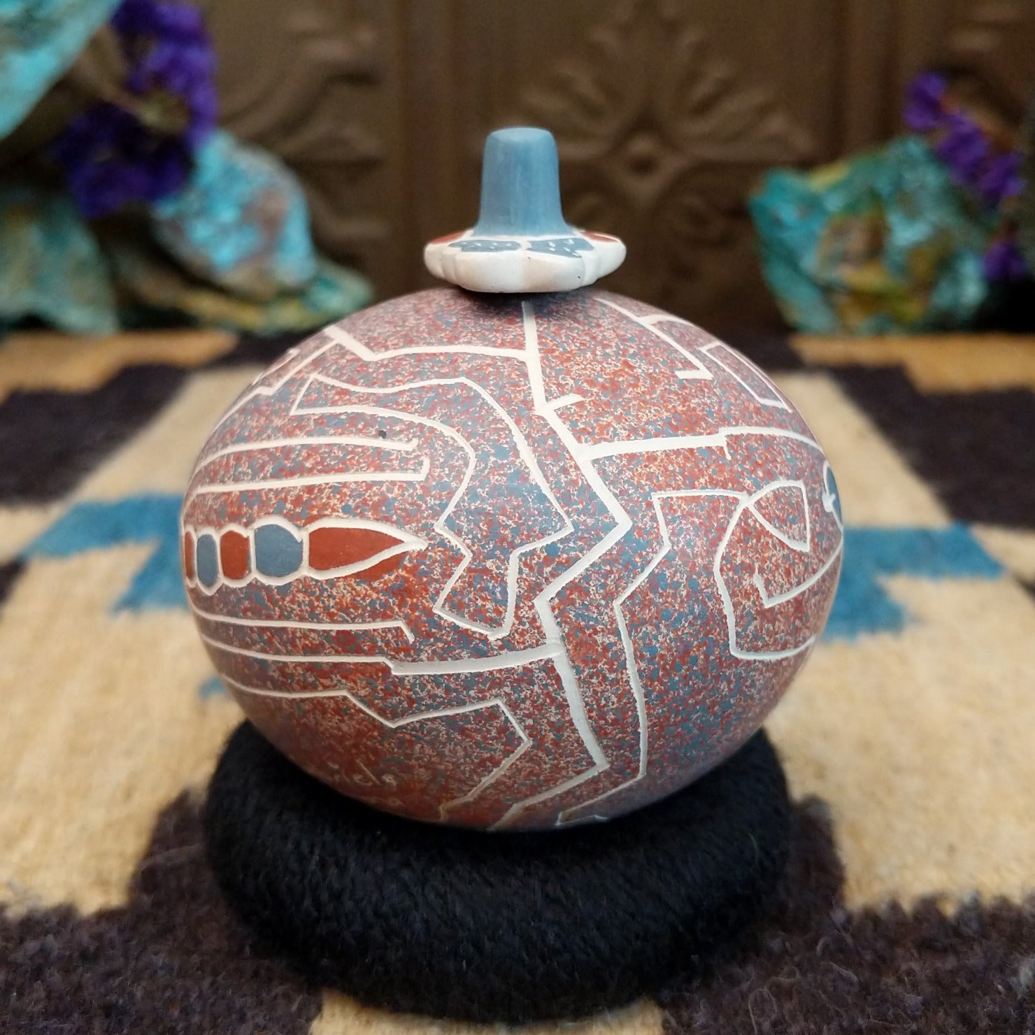Round lidded Mata Ortiz pottery vessel featuring a dragonfly design in blue and clay tones with etched geometric background patterns.