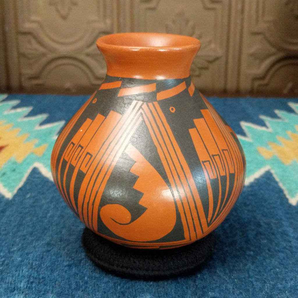 Terracotta toned clay with black geometric designs.