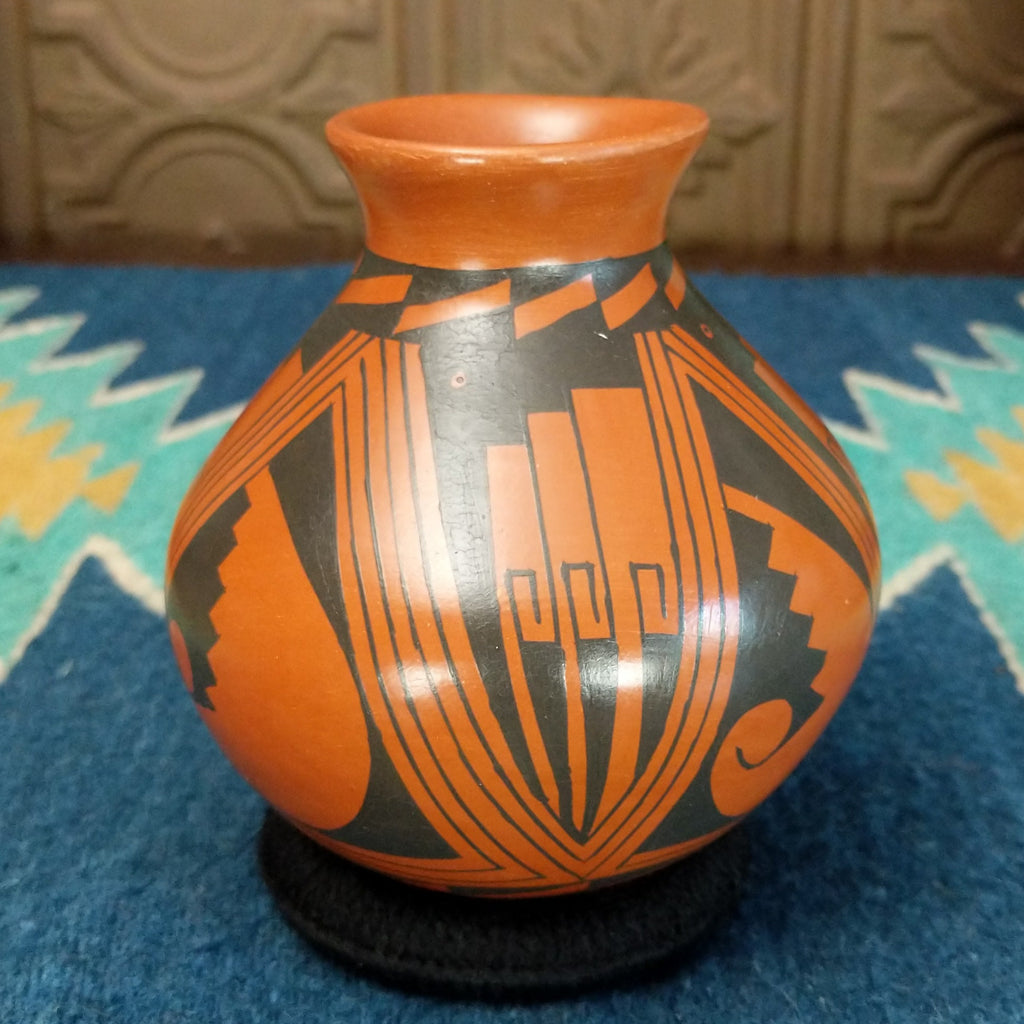 Terracotta toned clay with black geometric designs.