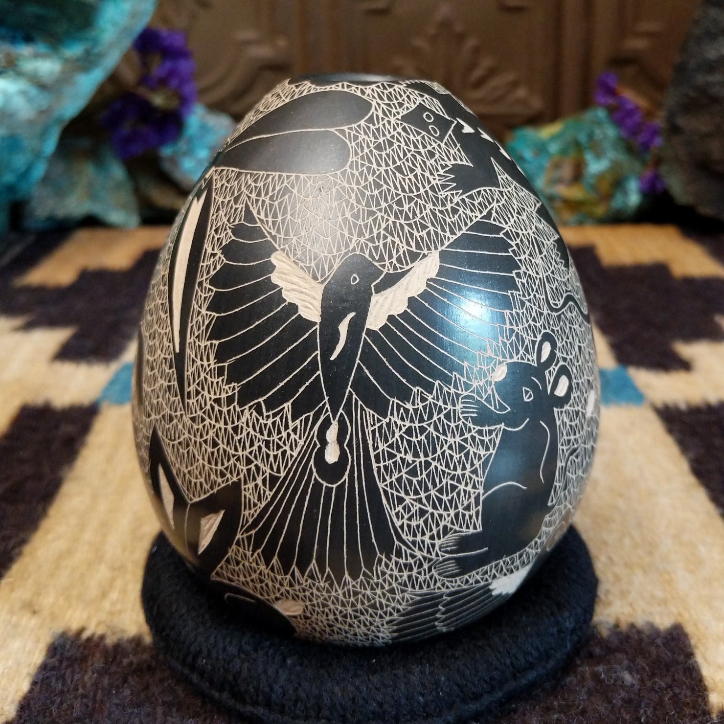 Egg-shaped Mata Ortiz pottery vessel with an etched black and white wildlife design featuring multiple stylized animals.