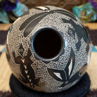 Egg-shaped Mata Ortiz pottery vessel with an etched black and white wildlife design featuring multiple stylized animals.