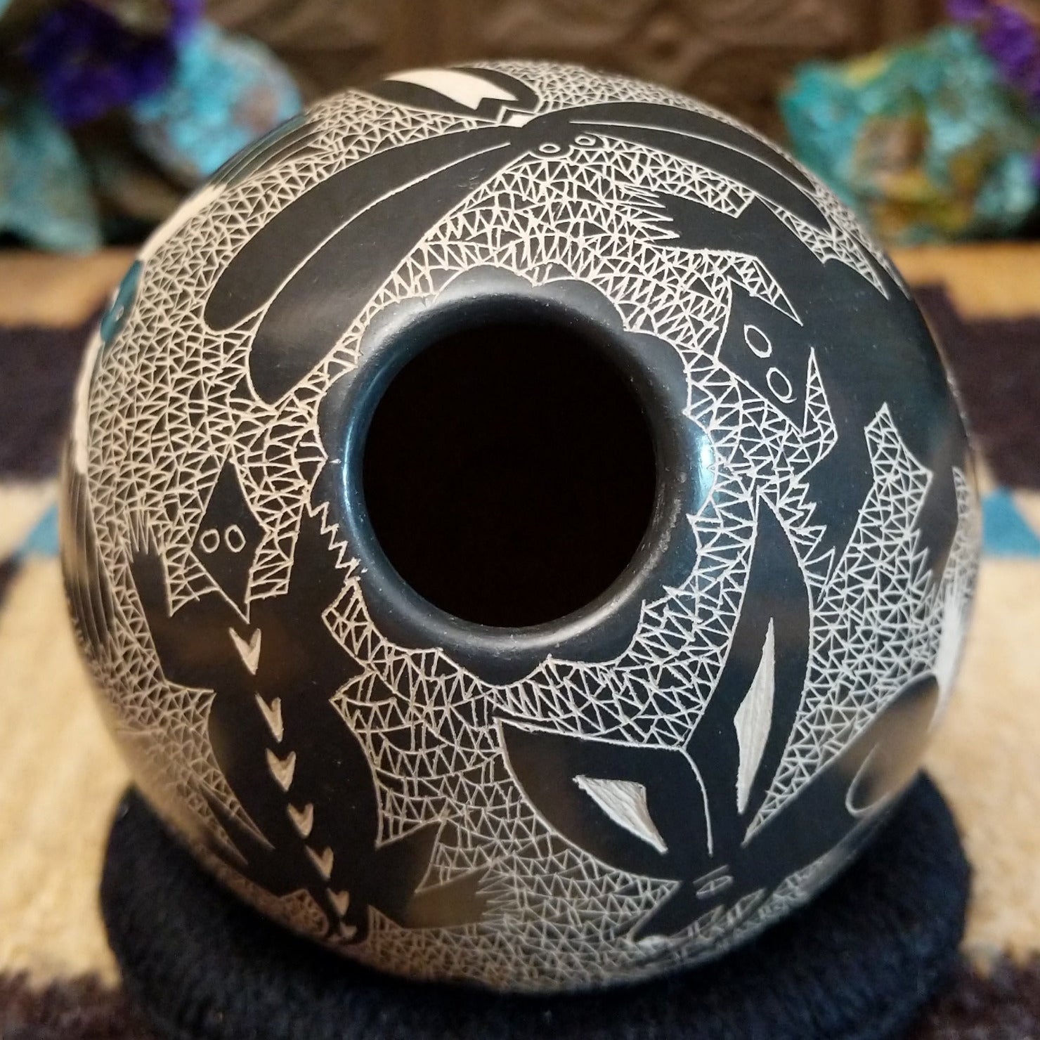 Egg-shaped Mata Ortiz pottery vessel with an etched black and white wildlife design featuring multiple stylized animals.