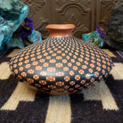 Low-profile Mata Ortiz pottery jar with a geometric checkerboard pattern in black and clay tones, featuring white dotted accents and a squared neck opening.