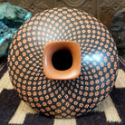 Low-profile Mata Ortiz pottery jar with a geometric checkerboard pattern in black and clay tones, featuring white dotted accents and a squared neck opening.